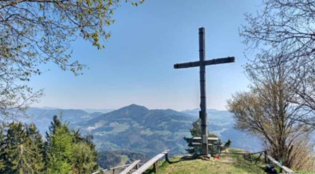 Zu sehen ist der Ausblick vom Haneggkogel, sowie ein einfaches Gipfelkreuz.